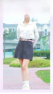 Détail d'une ceinture fine en cuir rose avec boucle dorée sur une jupe grise