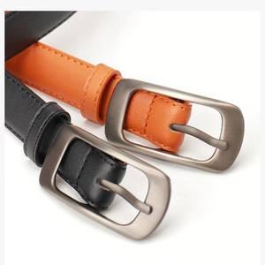 Gros plan de ceintures en cuir noir et orange avec boucles en métal et surpiqûres
