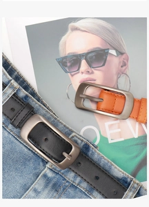 Détail de ceintures en cuir noir et orange avec boucles en métal sur un jean bleu