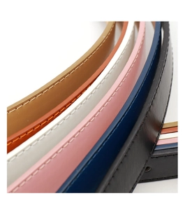 Détail de fines ceintures en cuir colorées avec surpiqûres précises et finitions lisses