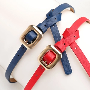 Minimalist leather belts with golden square buckles in navy and red on a white stand