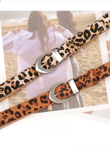 Detail of leopard print PU leather belts with silver metal buckles on a magazine backdrop