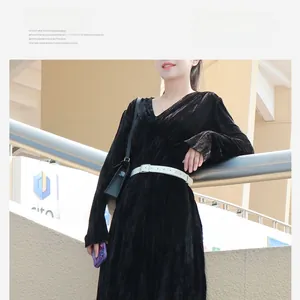Detail eines schmalen weißen Ledergürtels mit Schnalle auf schwarzem Samtplisseekleid
