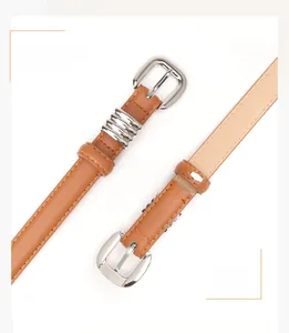 Detail van een smalle bruine kunstlederen riem met zilveren gesp en metalen ringen