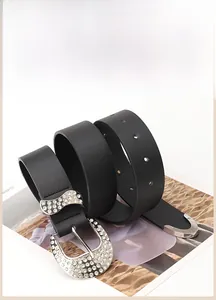 Close-up of black leather belt featuring rhinestone-encrusted buckle and metal end tip