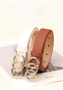 Detail of thin white and brown belts with triple gold rings on a fashion card