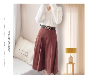 Elegant thin black belt with triple gold interlocking rings on a red pleated skirt