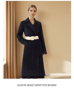 Détail d'une ceinture large élastique crème avec boucle recouverte sur un manteau noir