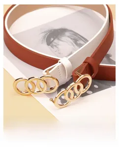 Flat lay of white and brown faux leather belts with three-ring golden buckle design