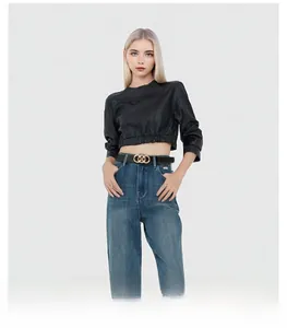 Close-up of a women's black leather belt featuring a gold three-ring buckle on denim jeans