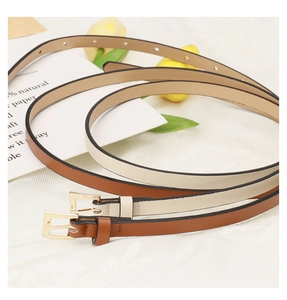 Close-up of brown and cream skinny PU leather belts with gold buckles on lace background