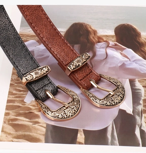 Detailed close-up of retro bohemian belts with embossed floral metal buckles and lychee texture
