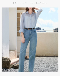 Detail of a slim brown leather belt on high-waist jeans with vintage metal floral buckle