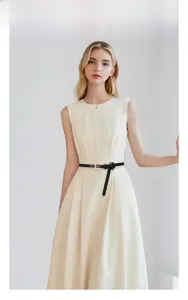 Detailed view of a slim black leather belt with a gold buckle on a beige dress