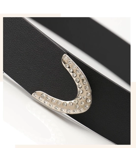Detail of black leather belt featuring a silver U-shaped buckle with sparkling rhinestones