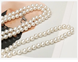 Detailed view of elegant white multi-layered pearl chain belt with silver metal lobster clasp