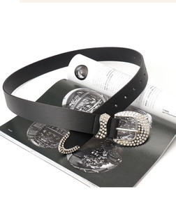 Detail of western black leather belt featuring sparkling rhinestone buckle and tip on magazines