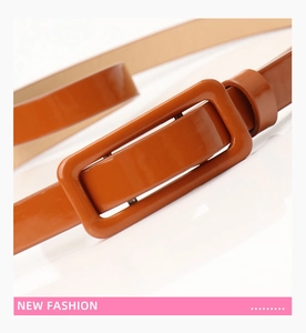 Close-up of caramel brown patent leather thin belt with matching rectangular buckle