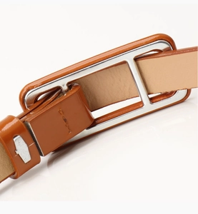 Detailed close-up of brown glossy leather belt with a silver rectangular metal buckle