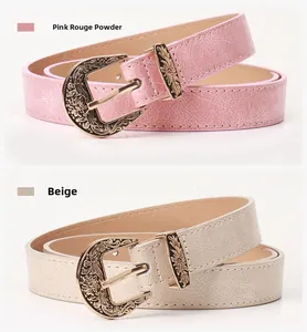 Close-up of vintage metal floral buckles on pink and beige faux leather belts