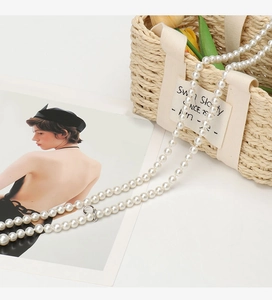 Detail of elegant white pearl waist chain with metal clasps on a woven basket backdrop
