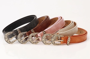 Detail of five slim vintage belts with engraved gold buckles and cracked leather texture