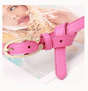 Détail d'une ceinture rose en cuir PU avec boucle ovale dorée et petit nœud élégant