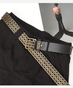 Detail eines schwarzen Punk-Ledergürtels mit mehrreihigen goldenen Ösen und Schnalle