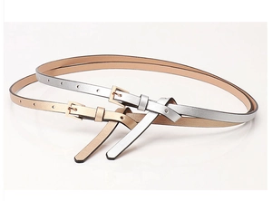 Detail of slim PU leather belts in metallic silver and champagne gold with elegant knot