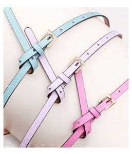Close-up of thin PU leather belts in pastel blue, lilac, and pink with gold buckles