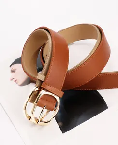 Close-up of brown PU leather belt with oval gold metal buckle on fashion magazine background