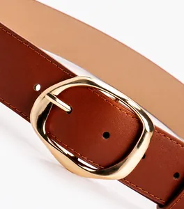 Close-up of golden oval buckle and brown PU leather belt with fine stitching details