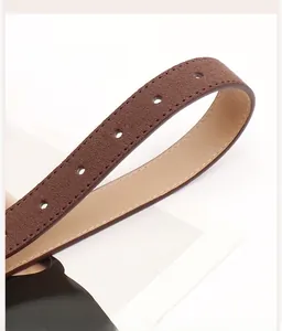 Détail macro d'une ceinture en daim marron avec coutures blanches et trous ronds