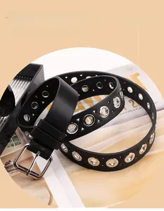 Detail shot of black punk belt with silver metal eyelets and classic square buckle