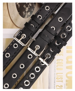 Detail of three punk style black leather belts with silver metal eyelets and pin buckle