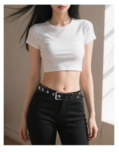 Detail view of a punk style black leather belt with silver eyelets on jeans