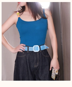 Détail d'une ceinture tressée bleu clair avec boucle blanche sur un jean en denim bleu
