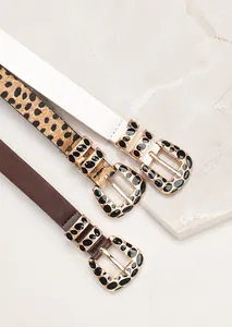 Detaillierte Nahaufnahme von schmalen Gürteln in Leopard, Weiß und Braun mit Goldschnalle