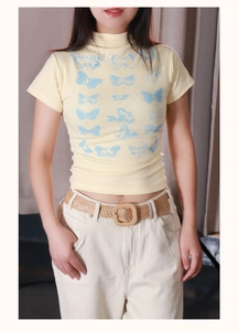 Détails des motifs papillon bleus sur T-shirt jaune avec ceinture tressée élégante
