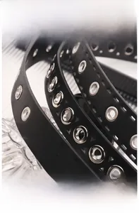 Detail of black PU leather belt with triple-row silver metal eyelets and fine stitching