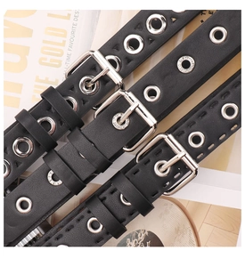 Detailed close-up of punk style black leather belts with silver metal eyelets and buckles