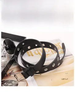 Detail of a black punk style leather belt with rows of silver eyelets and a square buckle