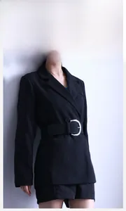 Close-up of a wide black faux leather belt with a silver semicircular buckle on a blazer