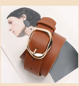 Detail of a brown PU leather belt featuring a modern irregular oval gold metal buckle