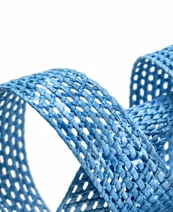 Détail macro d'une ceinture en paille tressée bleu ciel montrant le motif de maille creuse