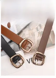 Close-up of black and brown leather belts with gold buckles on fashion magazines