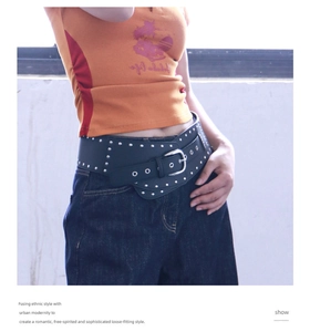 Détail d'une ceinture large Y2K noire avec rivets argentés sur un jean en denim