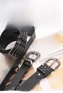 Détail de trois ceintures en cuir noir de style punk avec rivets argentés et boucles gravées