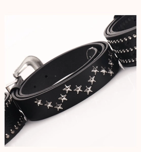 Détail macro d'une ceinture punk en cuir noir avec des clous en forme d'étoile argentée