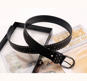 Détail de la ceinture punk noire avec rivets métalliques et boucle argentée polie